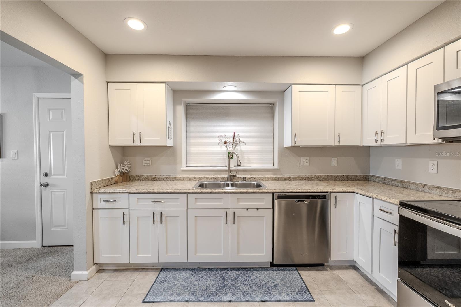 Bright and beautifully maintained kitchen with neutral finishes, abundant cabinet storage, and modern appliances. The open layout allows light to travel through the space, giving it an airy and inviting feel.