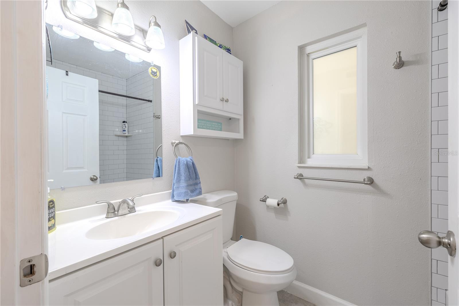 An alternate view of the guest bath showing the bright window and refreshed finishes that make the space feel crisp, clean, and ready to enjoy.