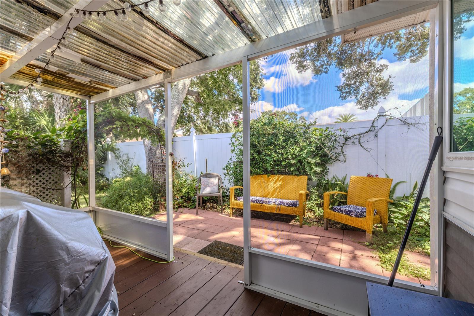 Charming screened-in patio with covered roofing and string lighting above. This inviting spot is perfect for enjoying Florida evenings without the bugs, blending relaxation and charm.