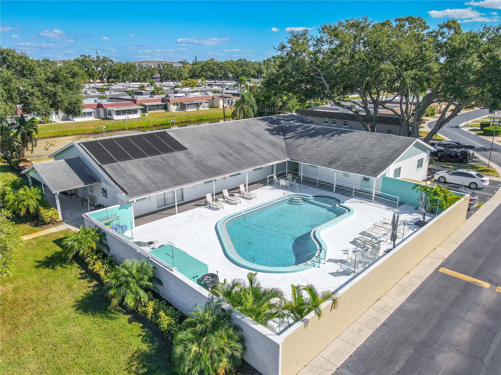 A closer look at the resort-style pool area surrounded by mature trees and lounge chairs, offering the perfect place to unwind under the blue sky.