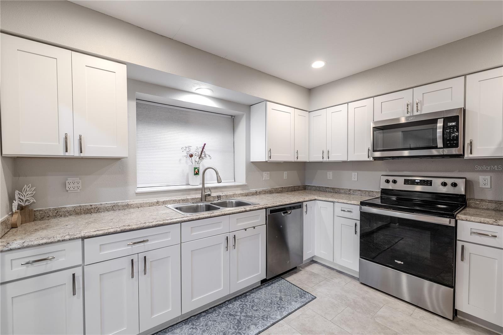 Bright and inviting kitchen with warm natural light streaming through the window above the sink. The thoughtful layout keeps everything within reach, while the soft neutral tones create a calm backdrop for daily life.