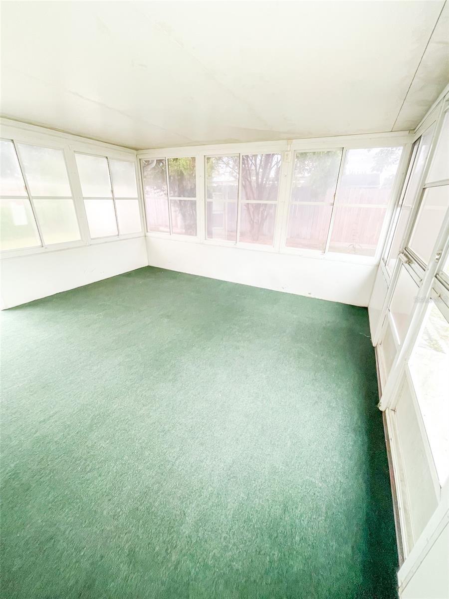 Large screened in patio features doors that open on both sides of the yard.