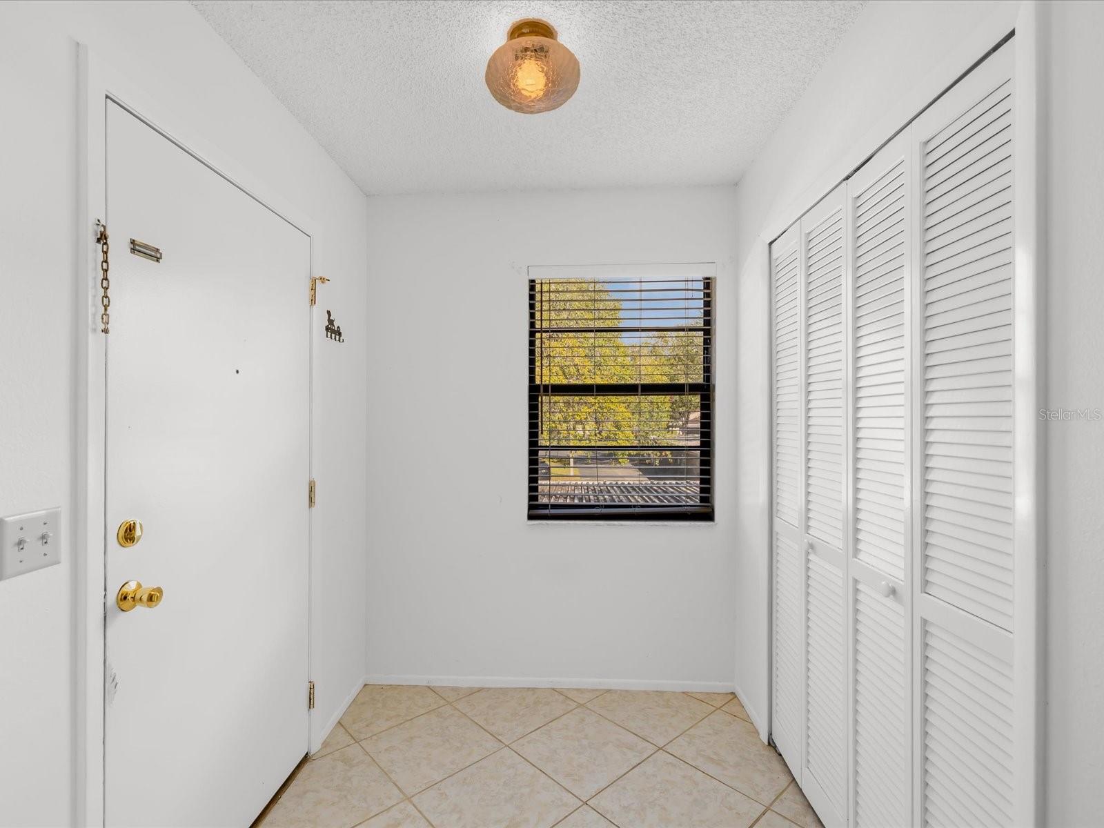 Spacious tiled foyer with large storage closet