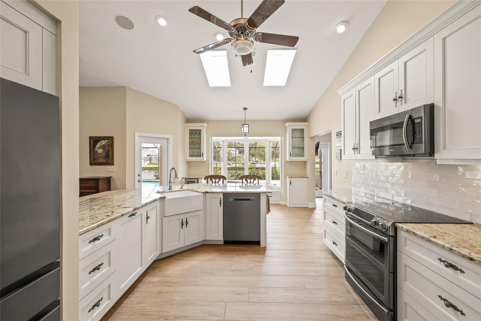 Porcelain farmhouse sink and built in dry bar with beverage fridge and bench seat overlooking the pool area.