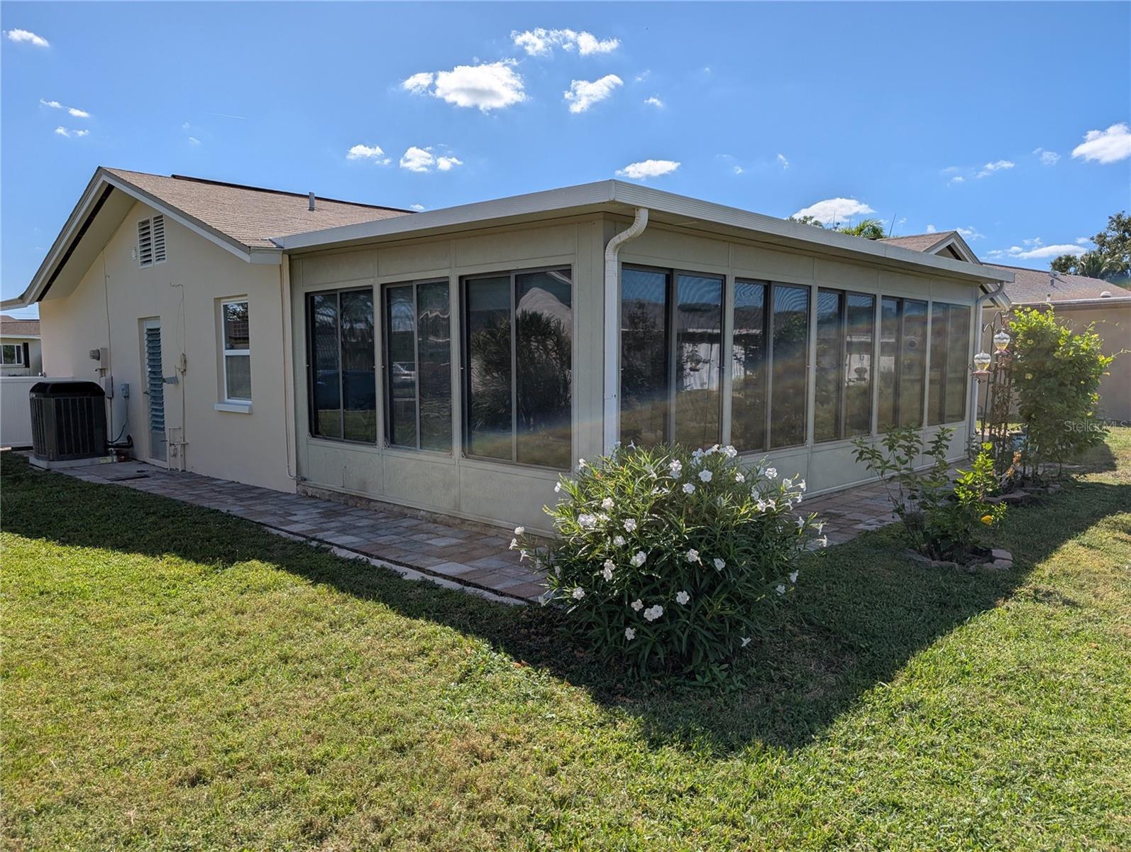 Exterior view of Florida room and paver walkway.  Garage side door access.  Trane HVAC system installed 2020.