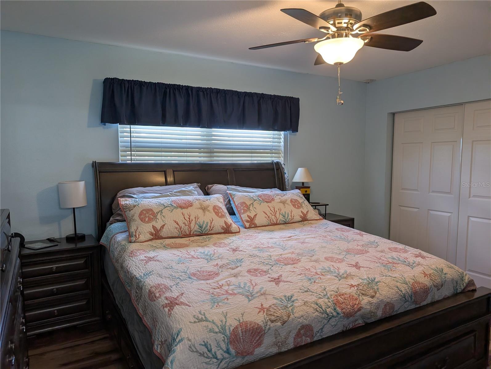 Primary bedroom features new closet doors, ceiling fan, faux wood blinds and new luxury vinyl flooring.
