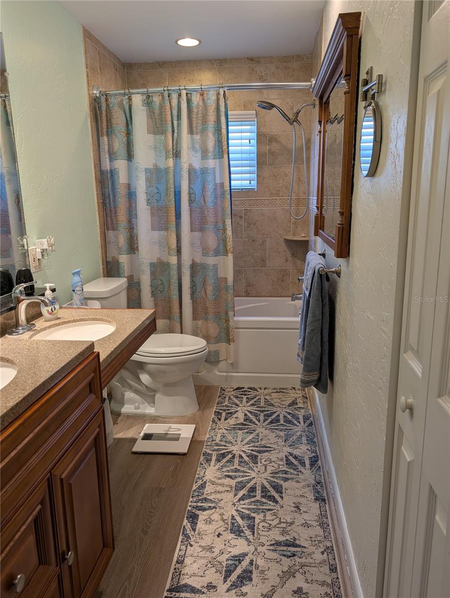 Main bathroom features custom dual sinks, one is HC accessible.  Linen closet to right. Bathtub with showerhead. Window provides extra light and ventilation.