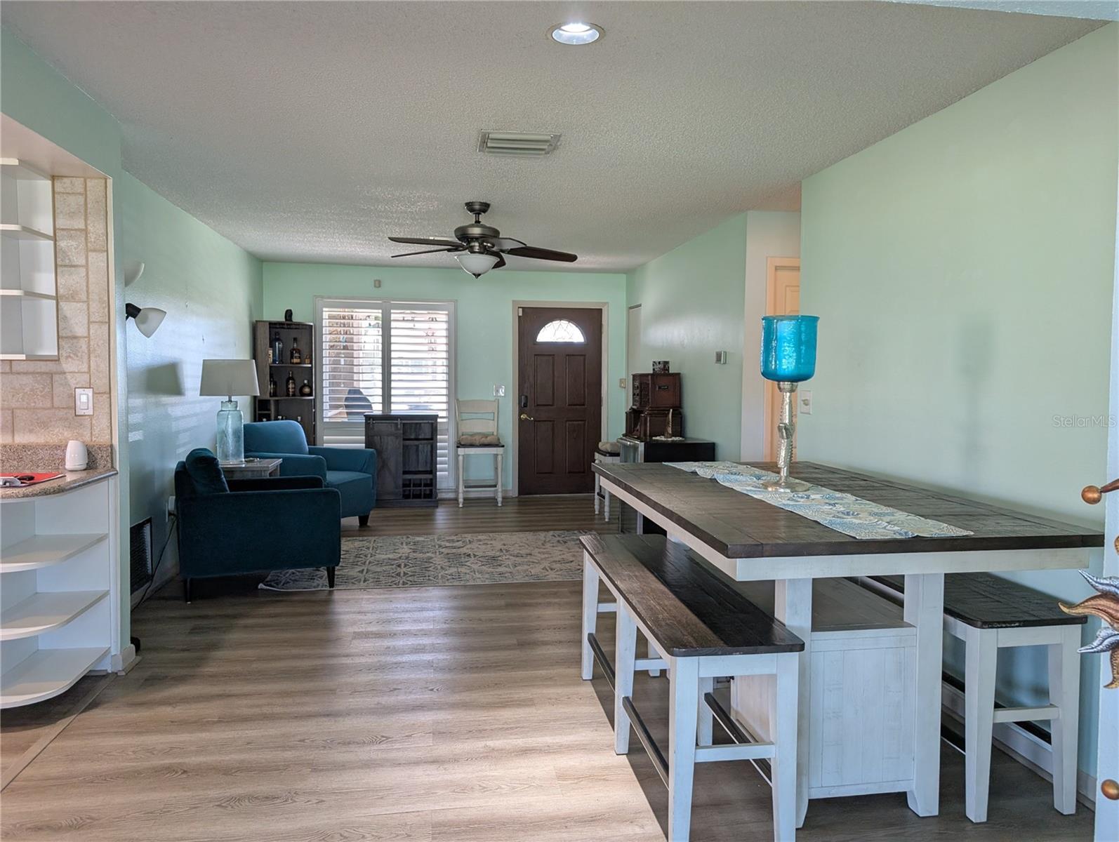 View from Florida room to front entry in living room, dining area and hallway into living area.