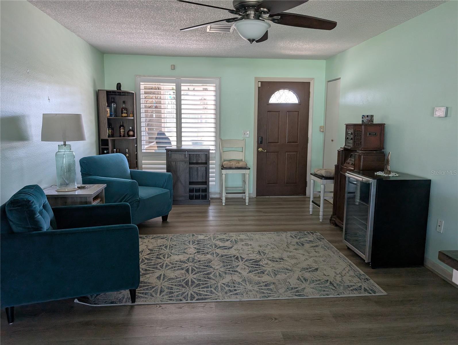 Living area features stylish vinyl flooring, ceiling fan and plantation shutters. Coat closet at entry.