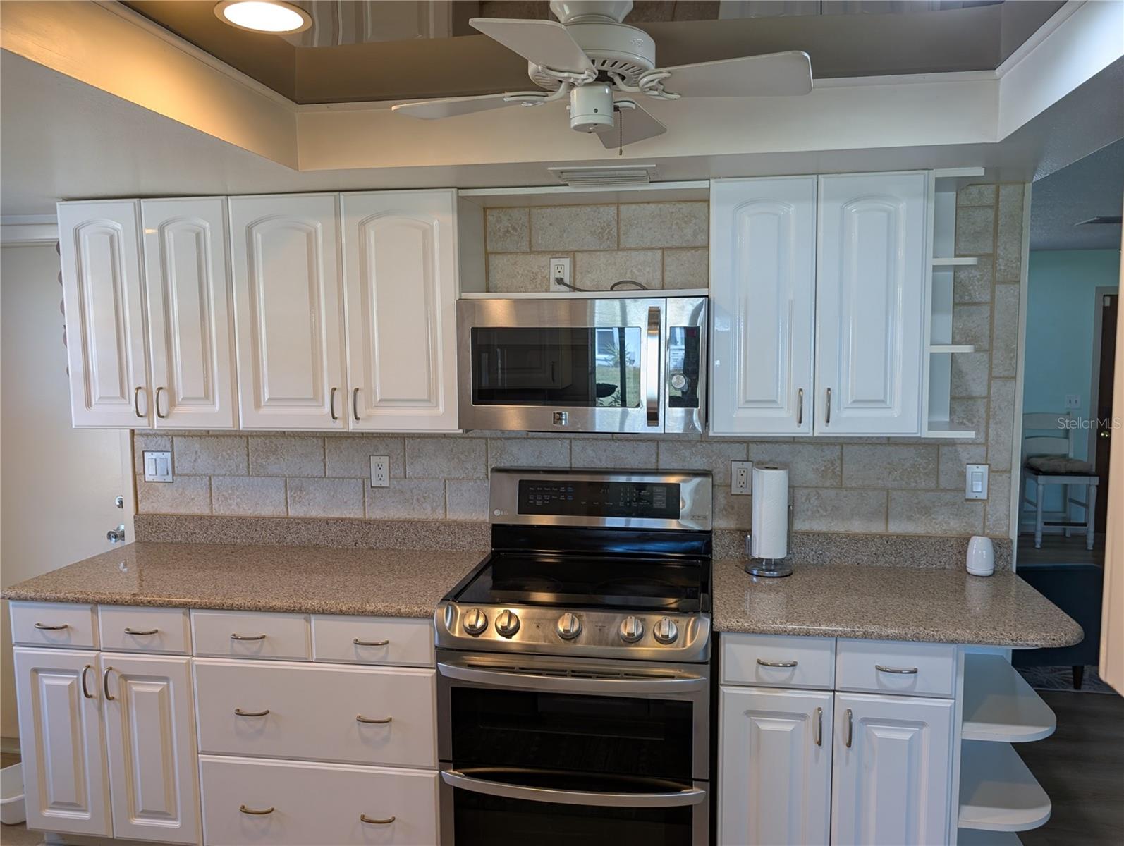 View from Florida room into kitchen. Beautiful stone backsplash behind LG range and microwave hood.