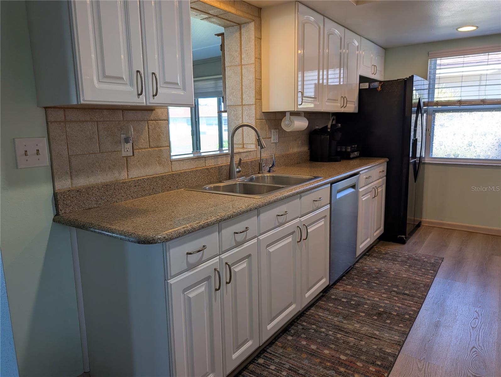 Kitchen view of pass thru into Florida room...convenient for entertaining.  Brand new Bosch dishwasher installed in 2025. The Whirlpool refrigerator has an in-door water/ice dispenser. Kitchen window is great for cooling things down when the cooking gets hot!