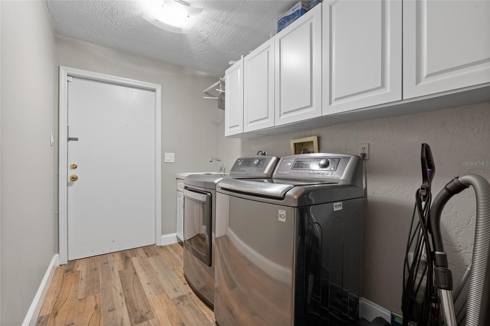 FULL SIZE LAUNDRY ROOM WITH STORAGE AND SINK. THE DOOR BRINGS YOU INTO THE GARAGE.