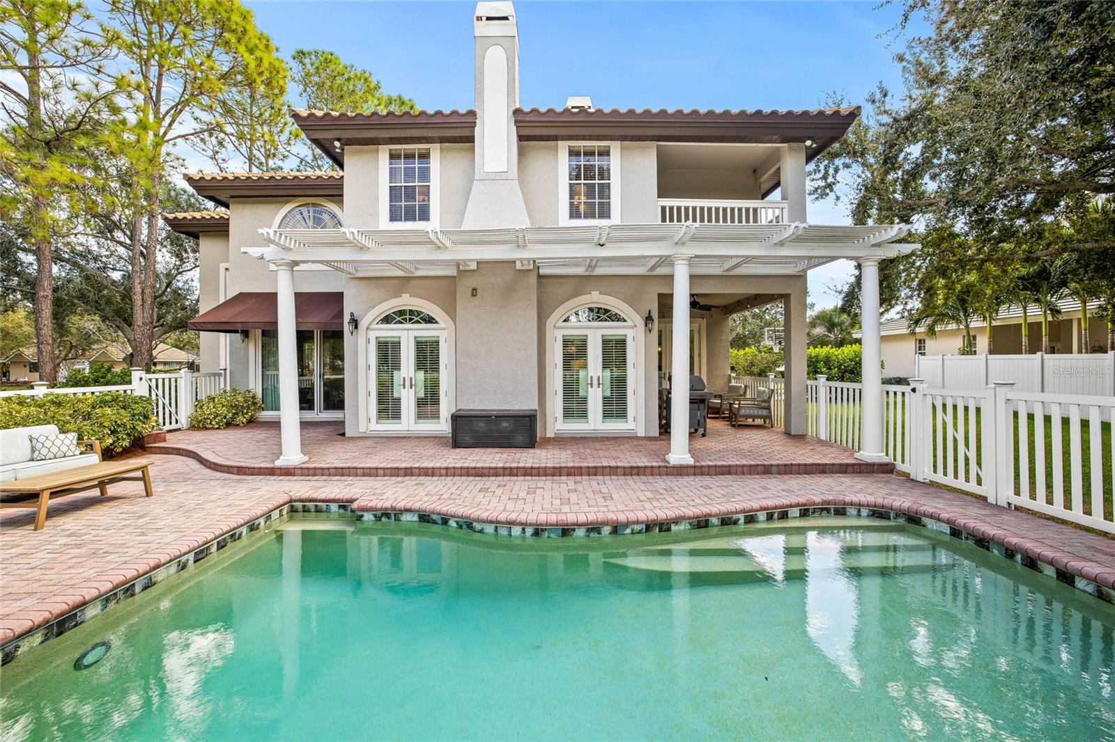 A gorgeous pergola sets the stage for outdoor events and gatherings around the fenced pool.