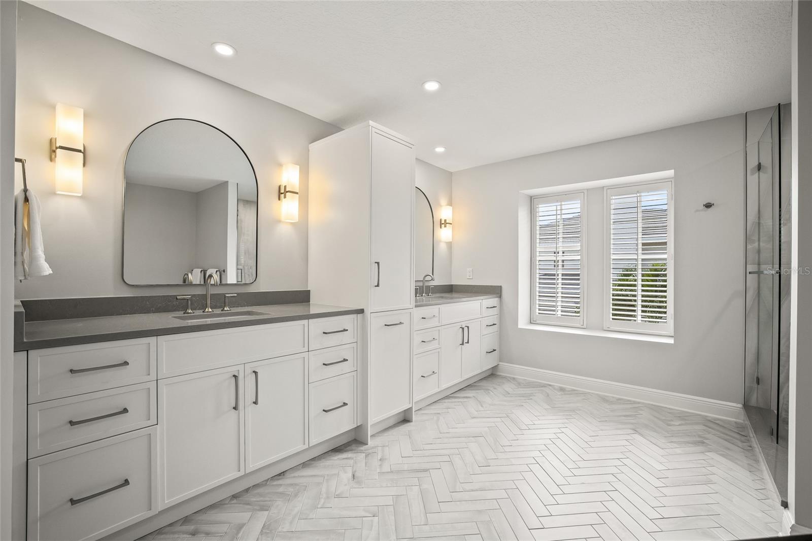 Separated dual sinks with custom cabinetry and storage.