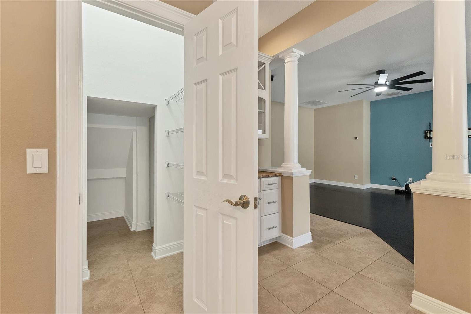 View into HUGE walk-in pantry with shelving on two sides and additional storage space that spans all the way back under the stairs