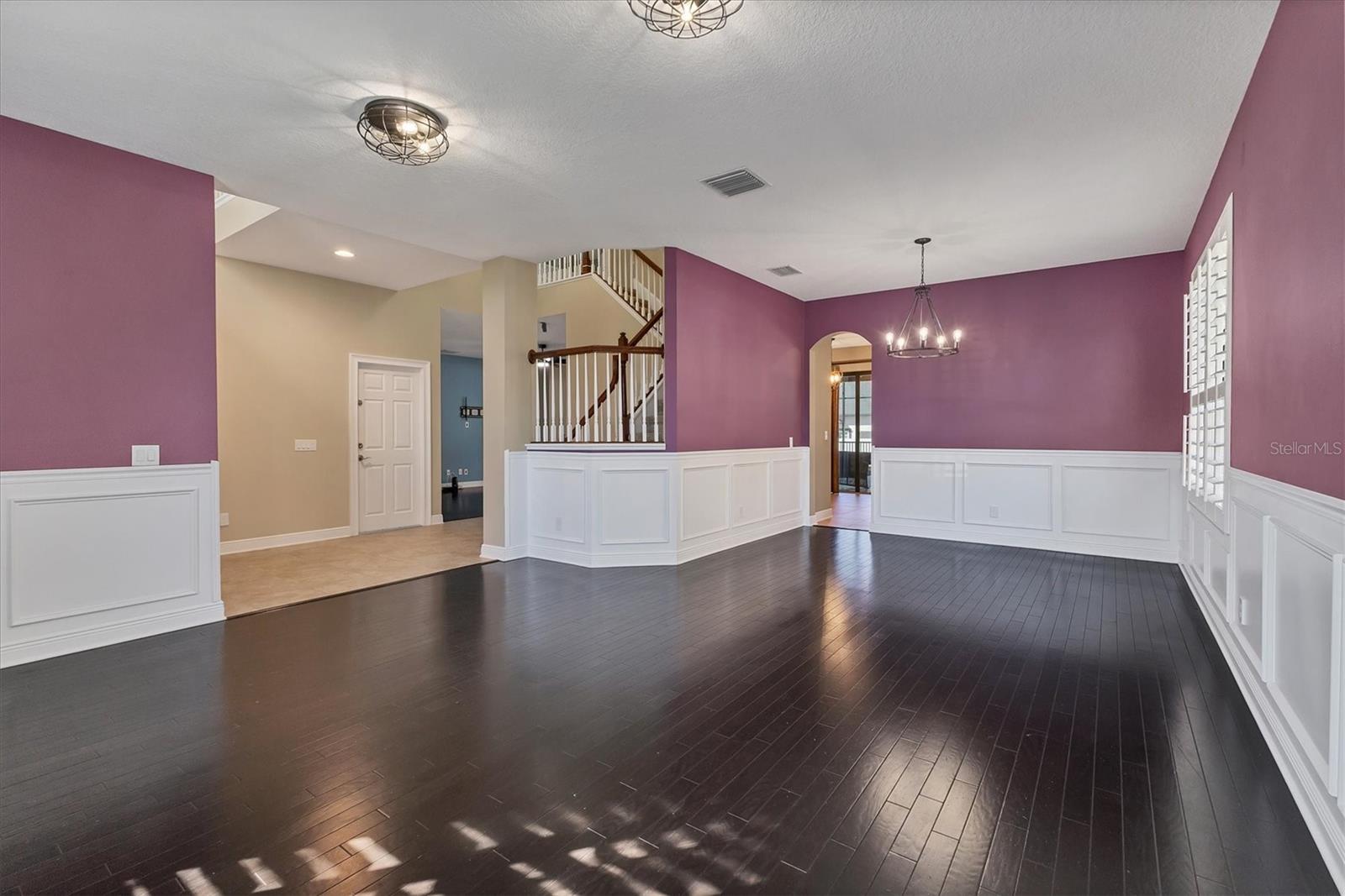 Large formal living/dining combo features rich wood floors and classic wainscoting that wraps the room with  elegant detail