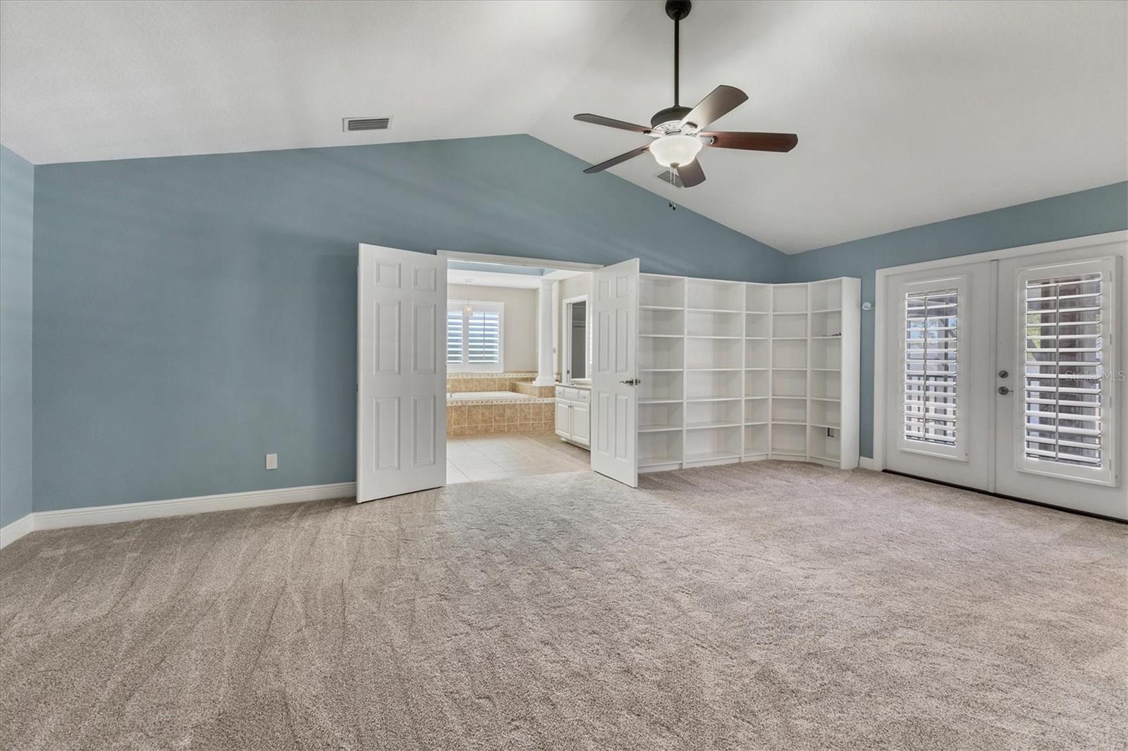 Generously sized primary suite with double door entry to spacious ensuite bathroom and built-in bookshelves