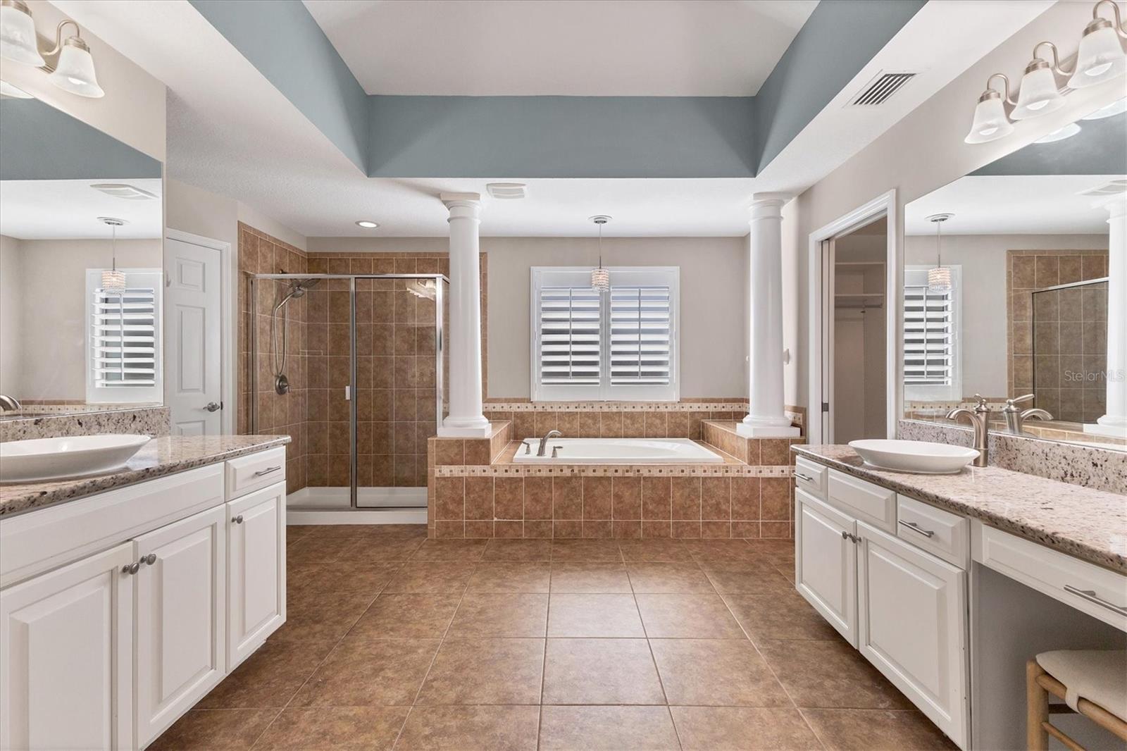 Beautiful ensuite bathroom accented with tray ceiling, stately columns around the garden tub, a spacious walk-in shower and separate vanities.