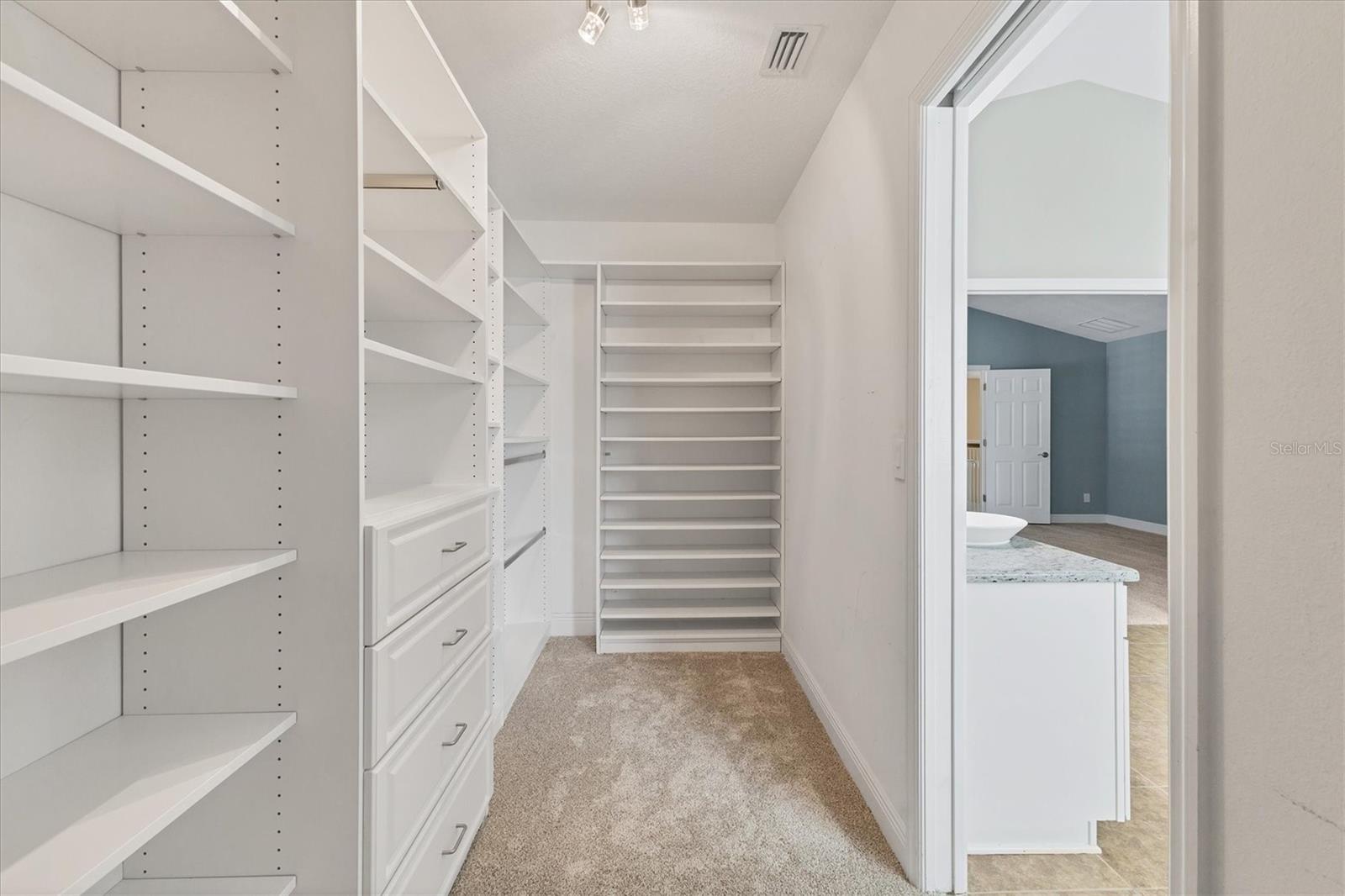 Full view inside the large custom walk-in closet by Closets By Design