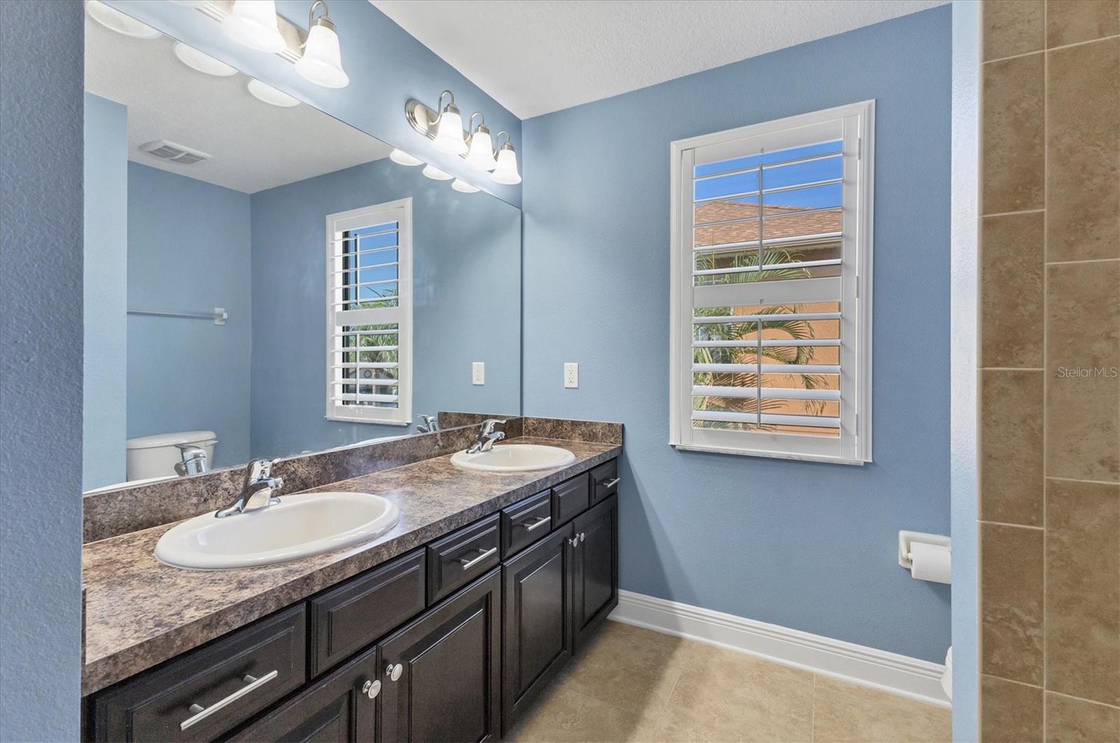 Upstairs bathroom for secondary bedrooms features tub/shower combo & dual sinks.