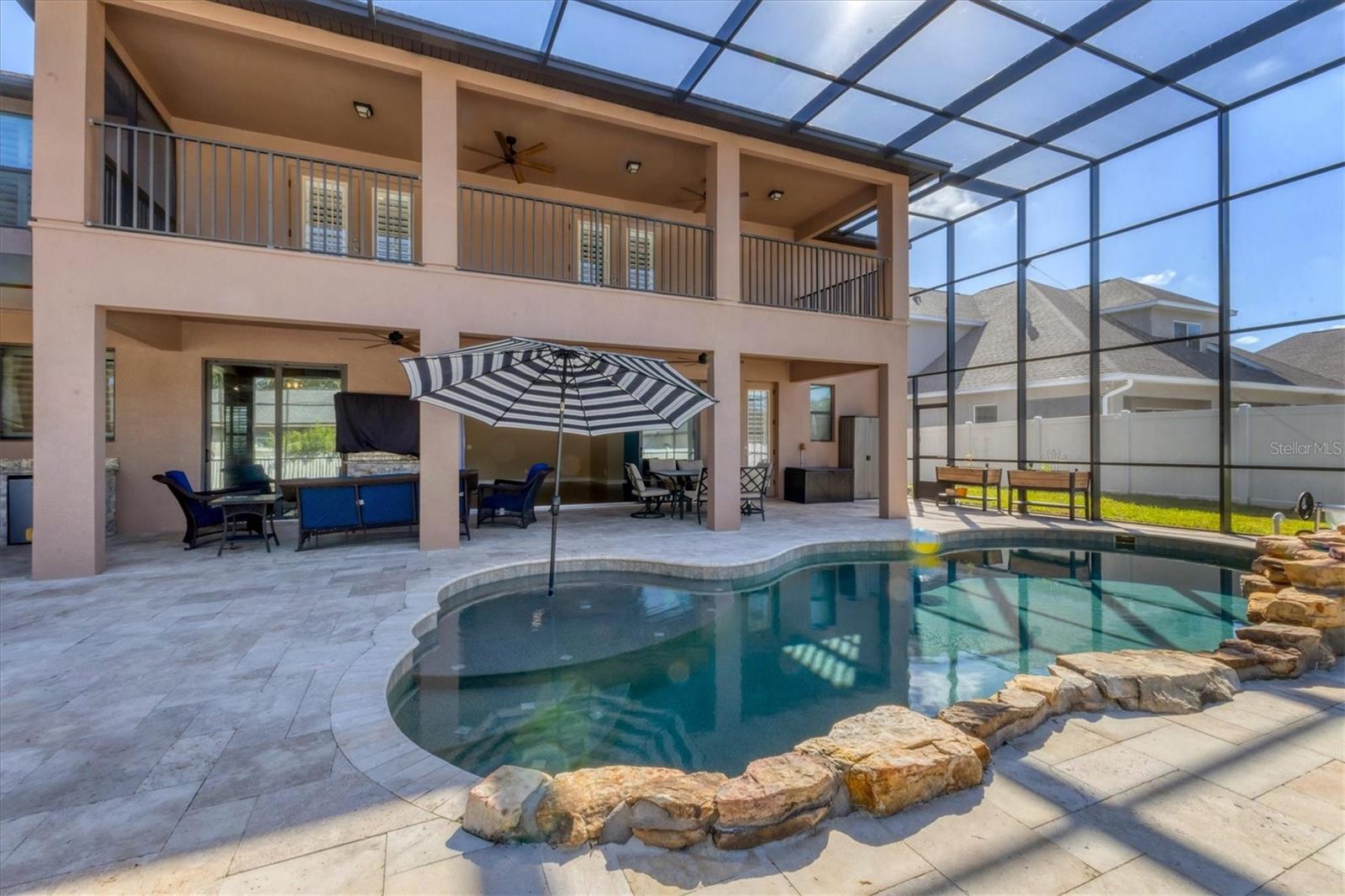 Refreshing pool with rock detail and a sunshelf with umbrella