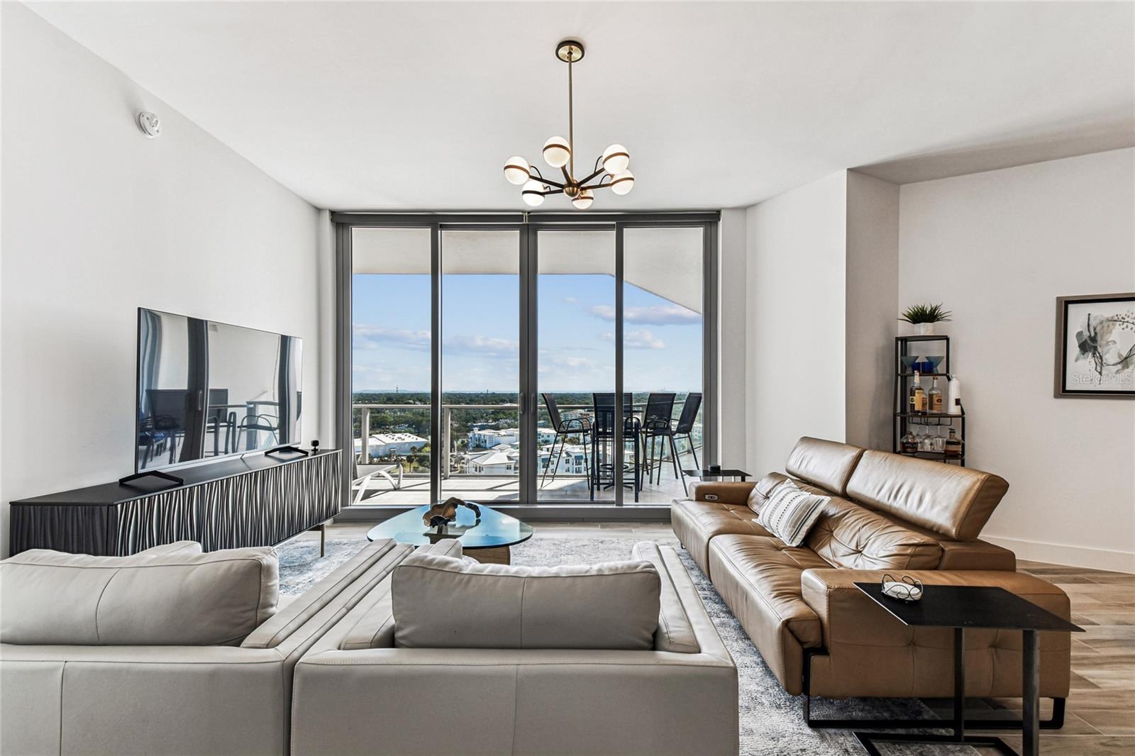 Bright, open living area with floor-to-ceiling sliders to the balcony and wide skyline views—an inviting spot to relax or entertain.