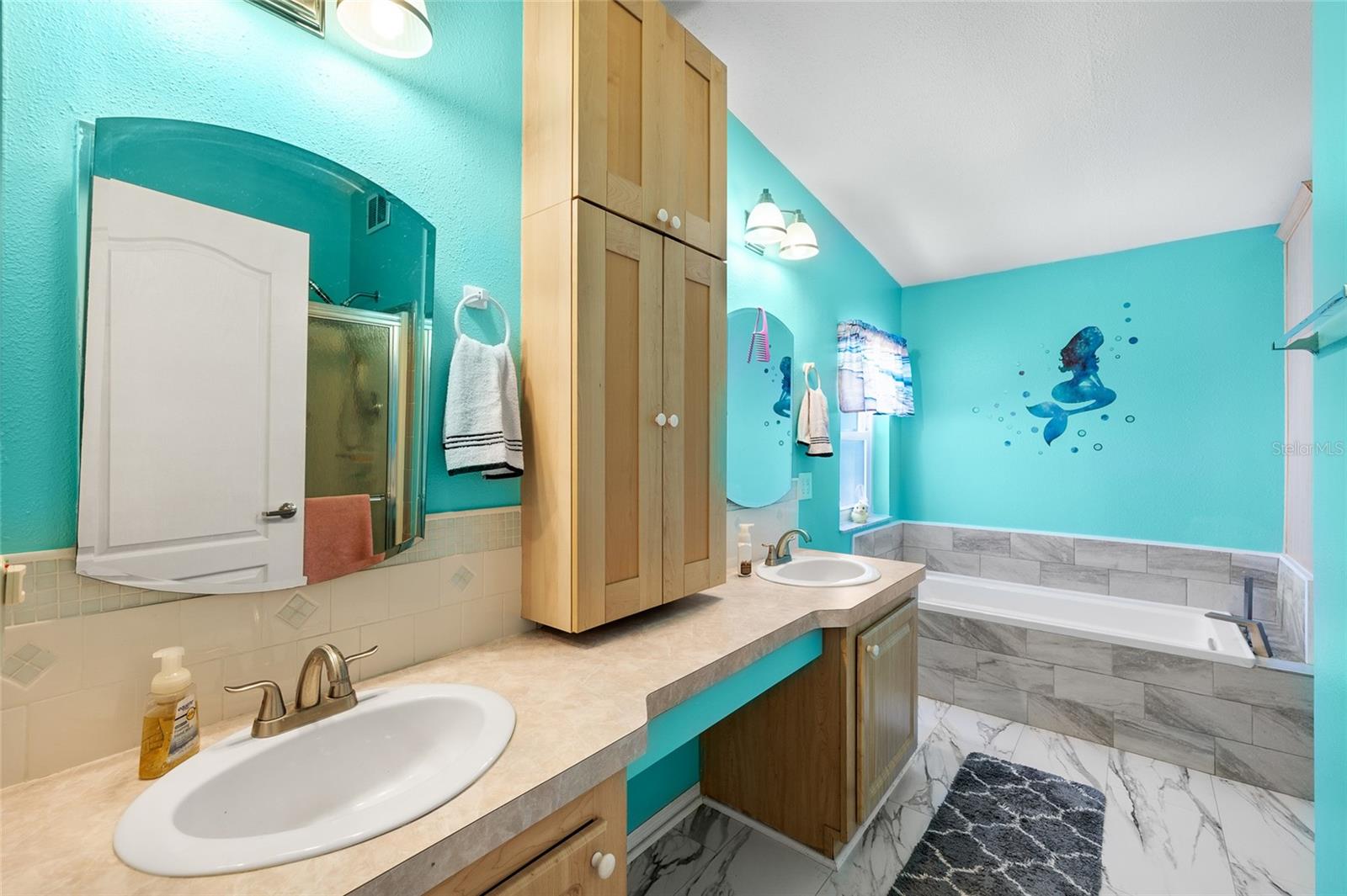 Primary bathroom offers a remodeled bathroom with double sinks, a garden tub, and step-in shower