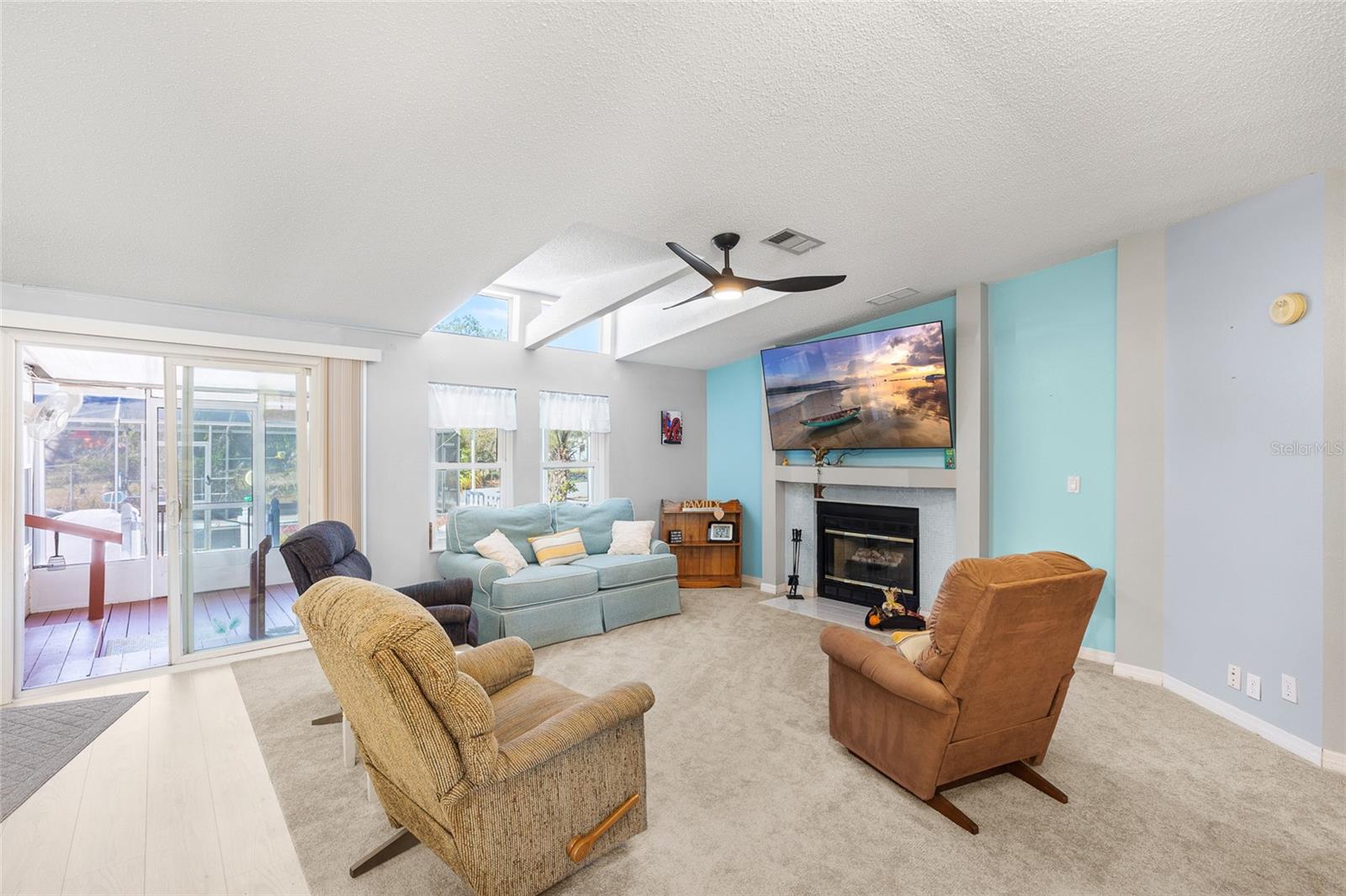 Living room with ceiling fan, fireplace, huge screen tv