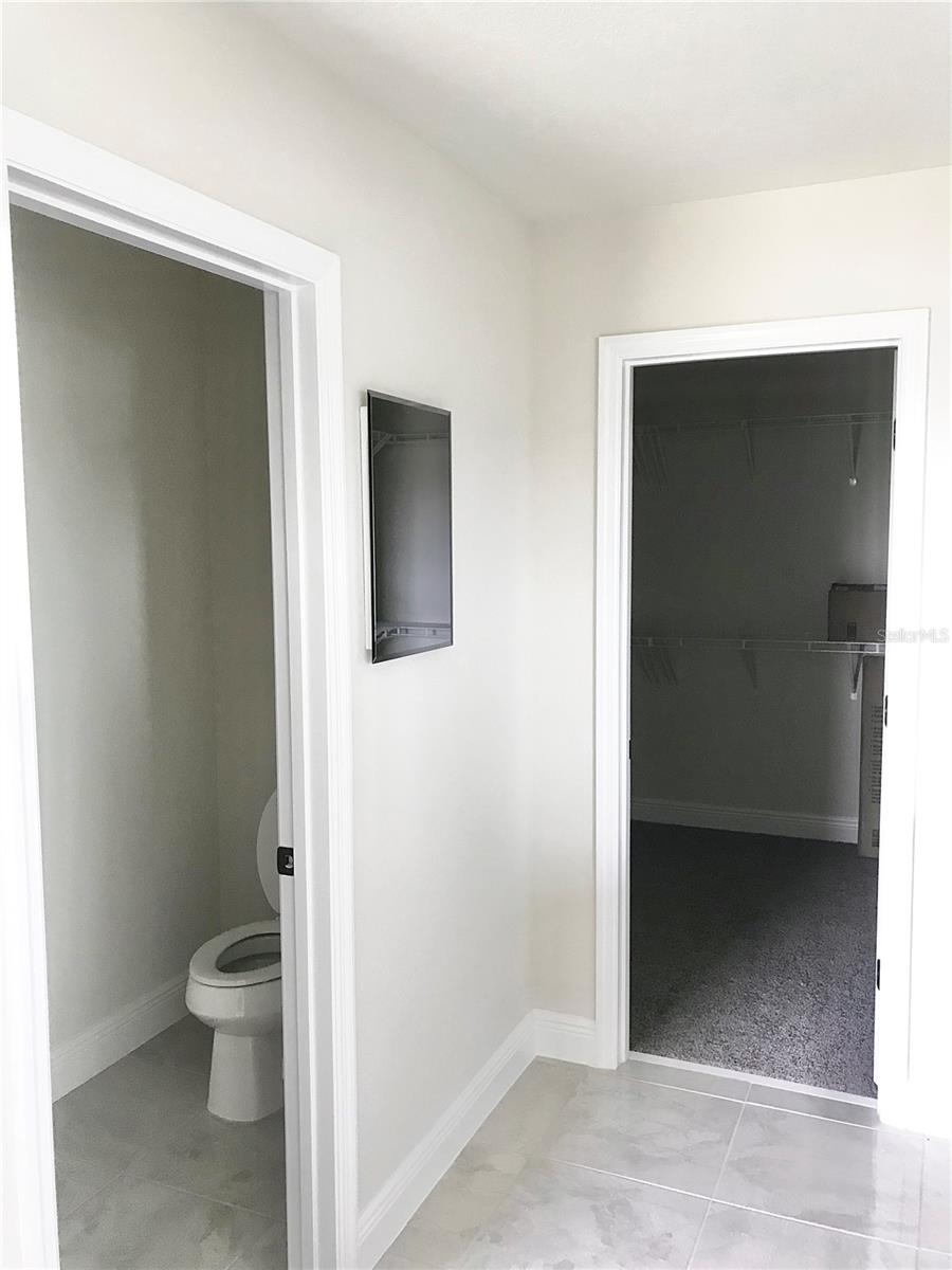 Master Bathroom toilet room and leading into master closet