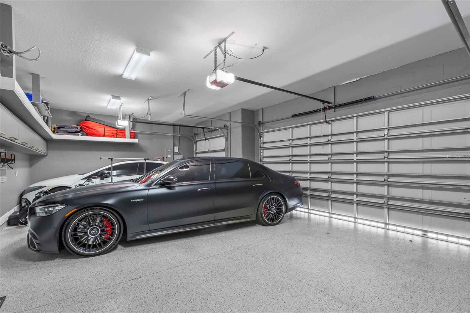 3-car garage with epoxy flooring and extra storage shelves.