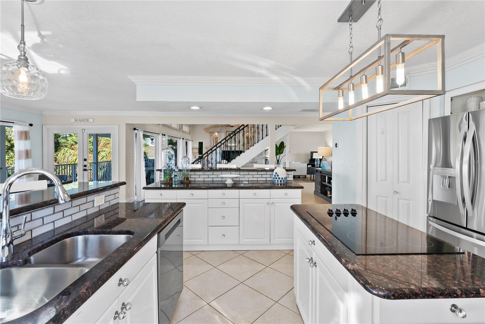 Chef’s kitchen with granite counters and stainless steel appliances upgraded lighting.