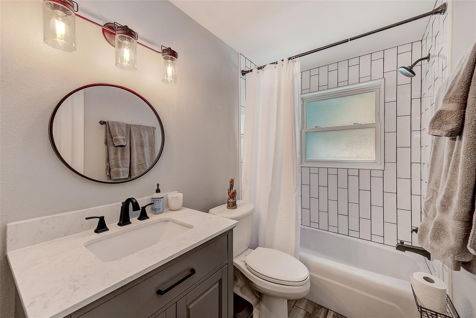 Barn door from living room enters into an updated second bathroom