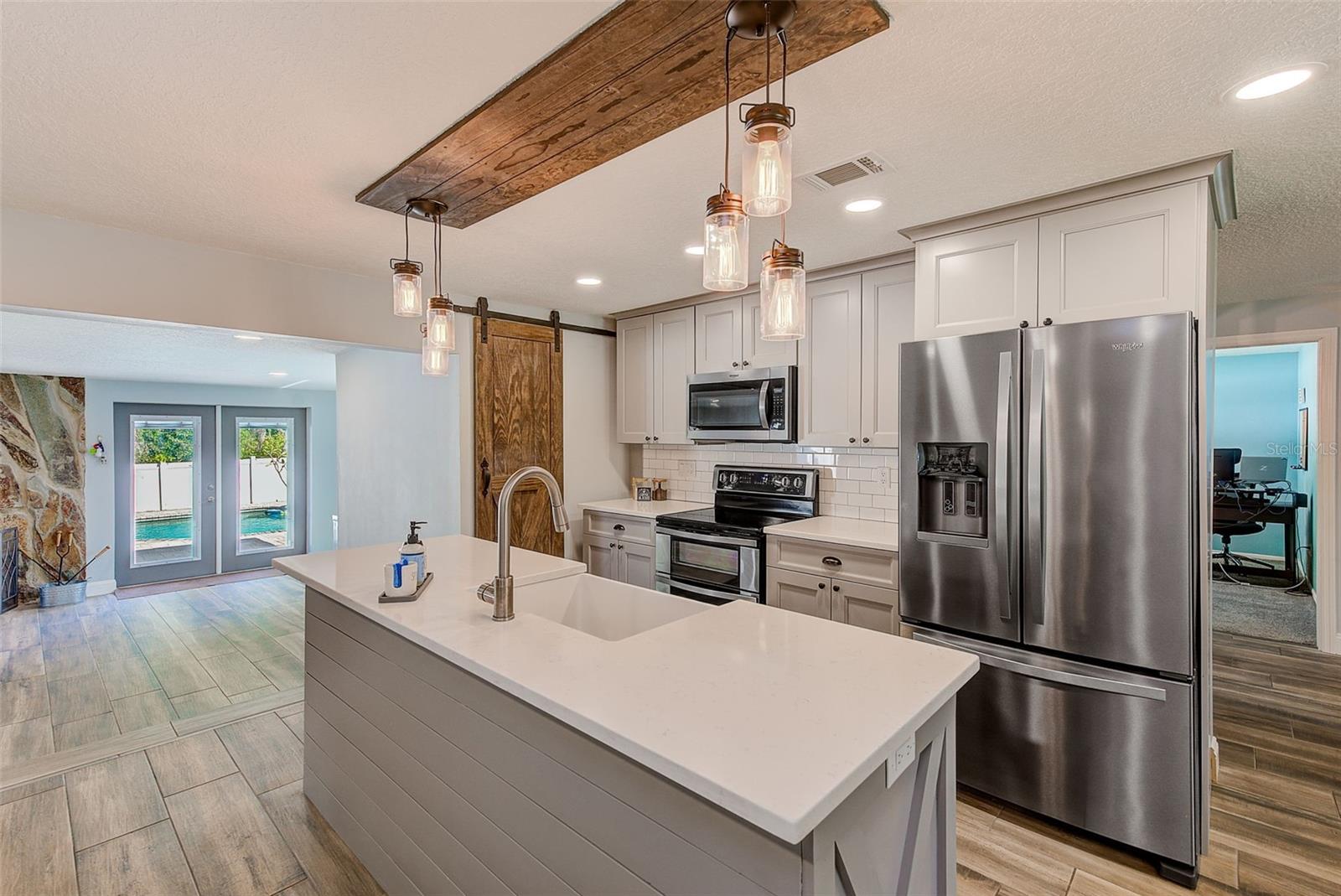 Elegant lighting above island with matching custom barn door to walk in pantry