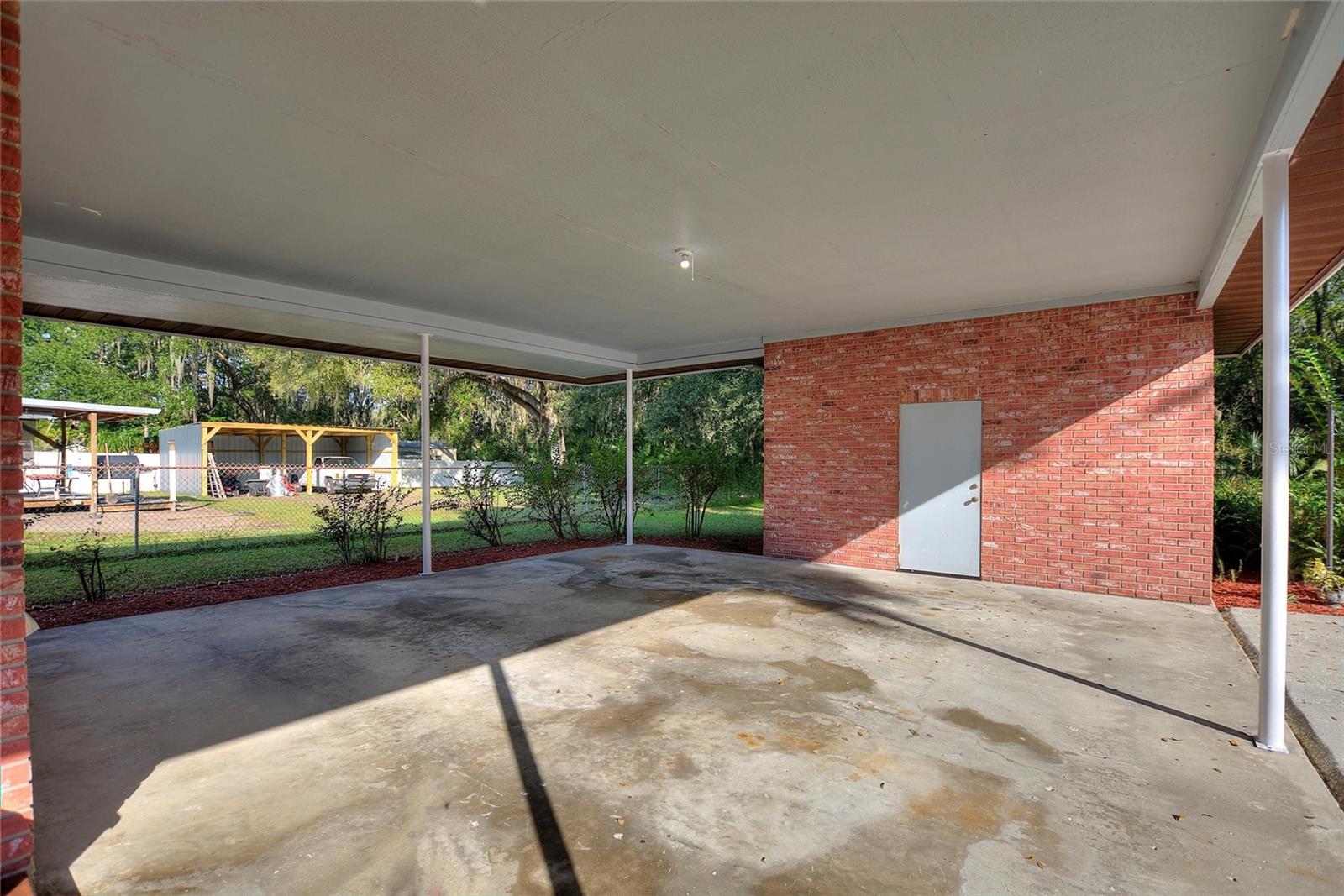 Double under-truss carport on the back side of the house.  The door leads into the workshop