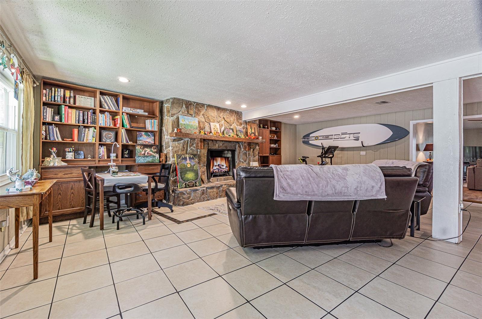 Expansive family room with custom built-in shelving and a wood burning fireplace.