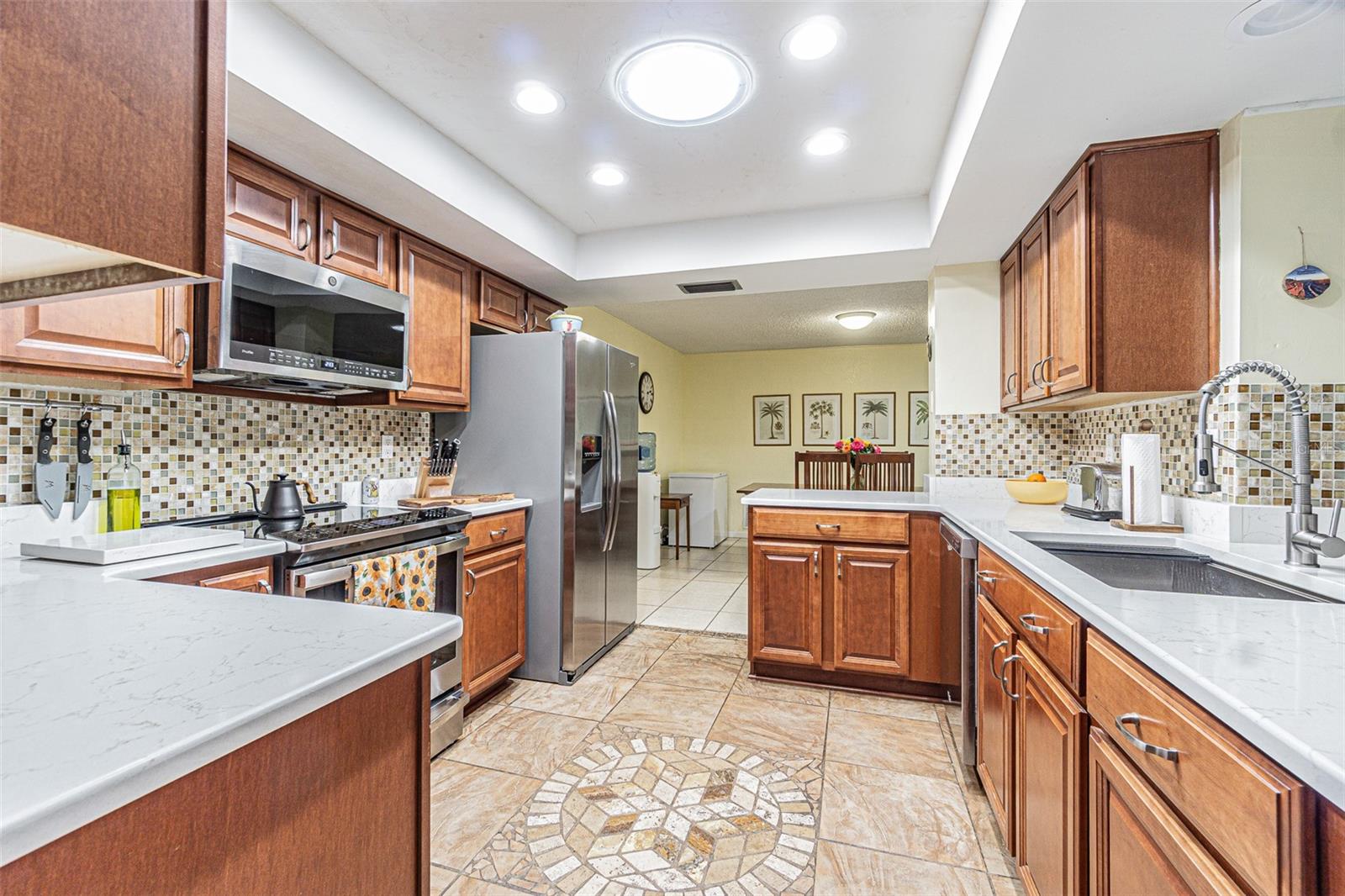 Custom Kitchen with tray ceiling looking into the eating area off the kitchen. The cerramic tile  floor also has custom inlaid tile.