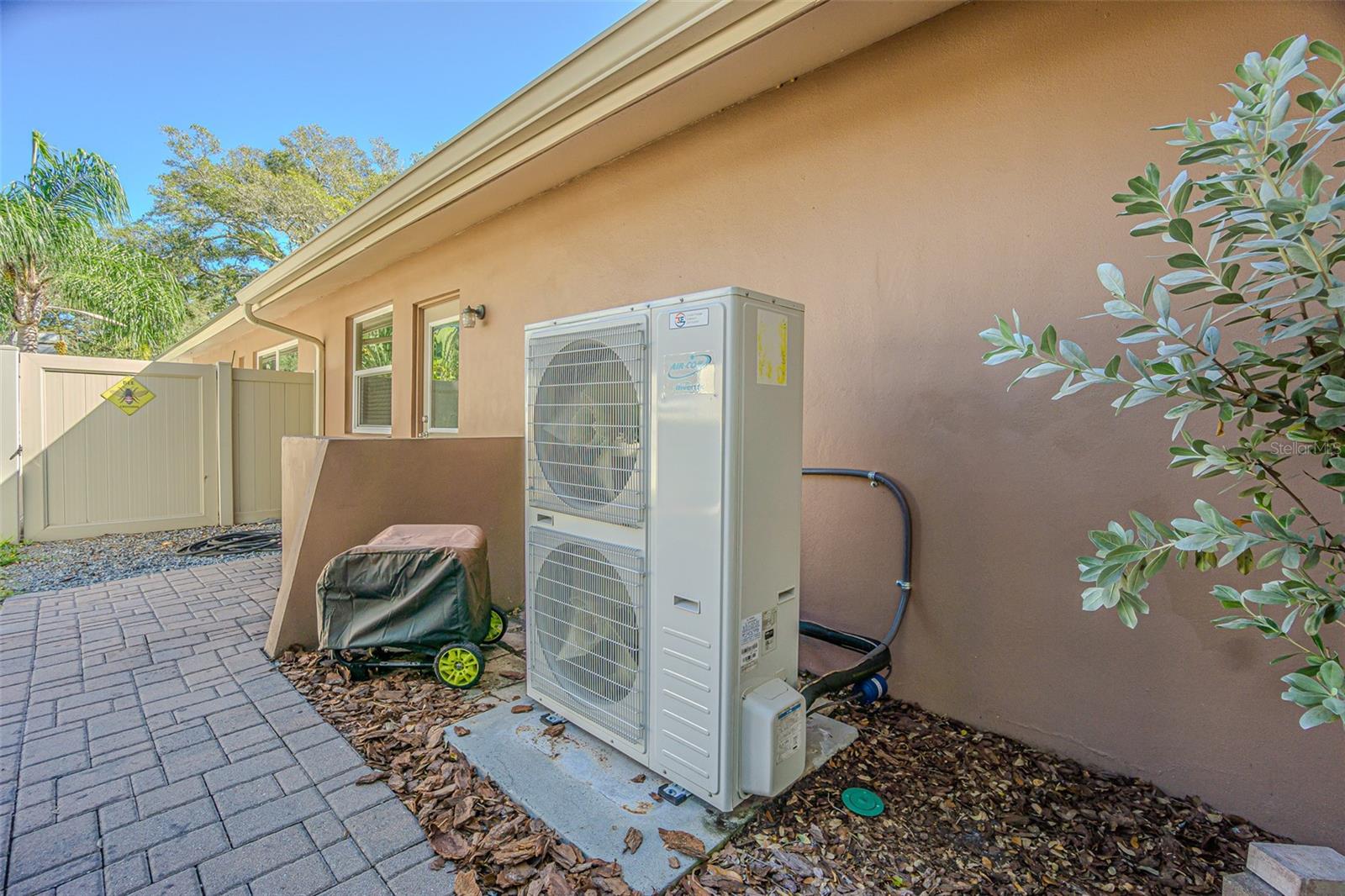 2024 3E 18 SEER Air-Com AC and pavered path to garage service door.