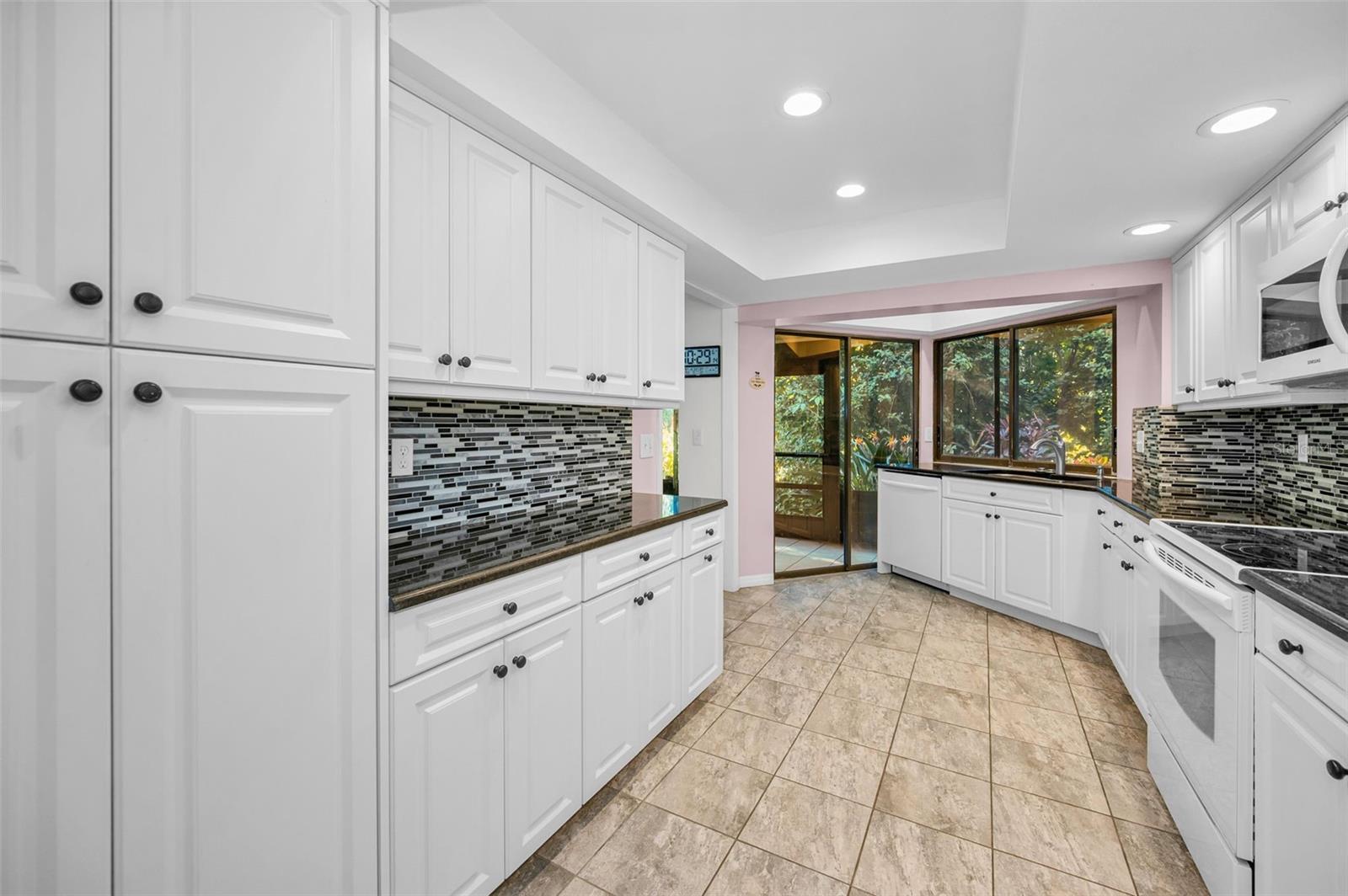 Kitchen with view to natural area and back screen porch.. Also has a pass thru window to back porch