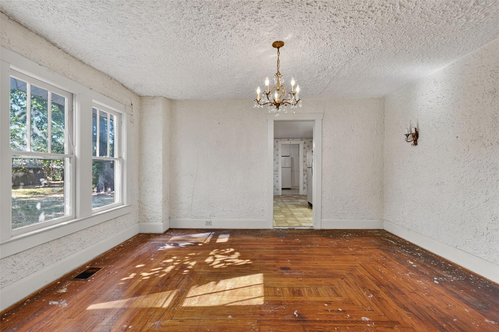 Dining room floors are same pattern as the living room.   Period chandelier and sconces on the wall.