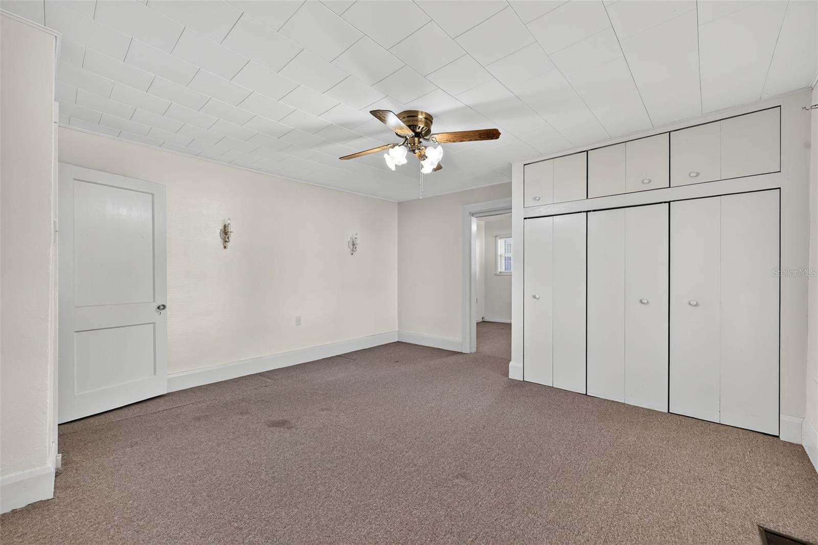Middle bedroom with large closet and storage above; period sconces on the far wall