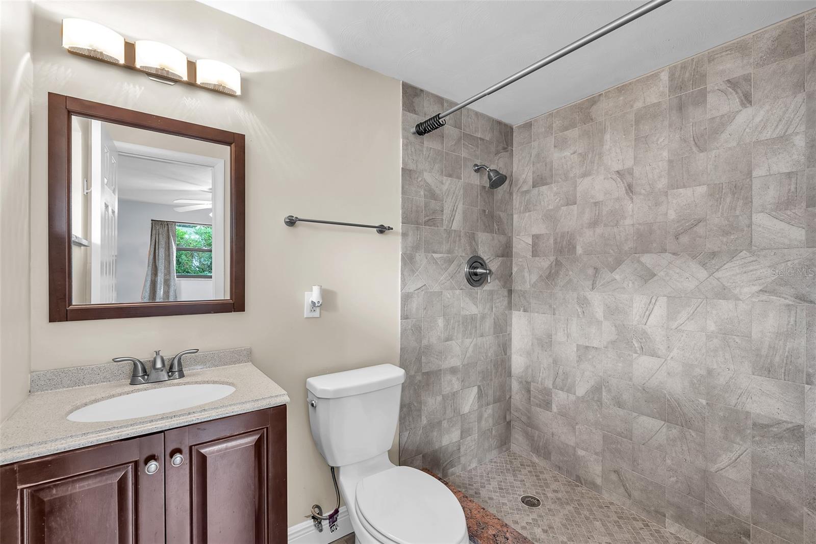 The Main ensuite bathroom with a walk-in shower, listello tile accents, and wood vanities with framed mirrors.