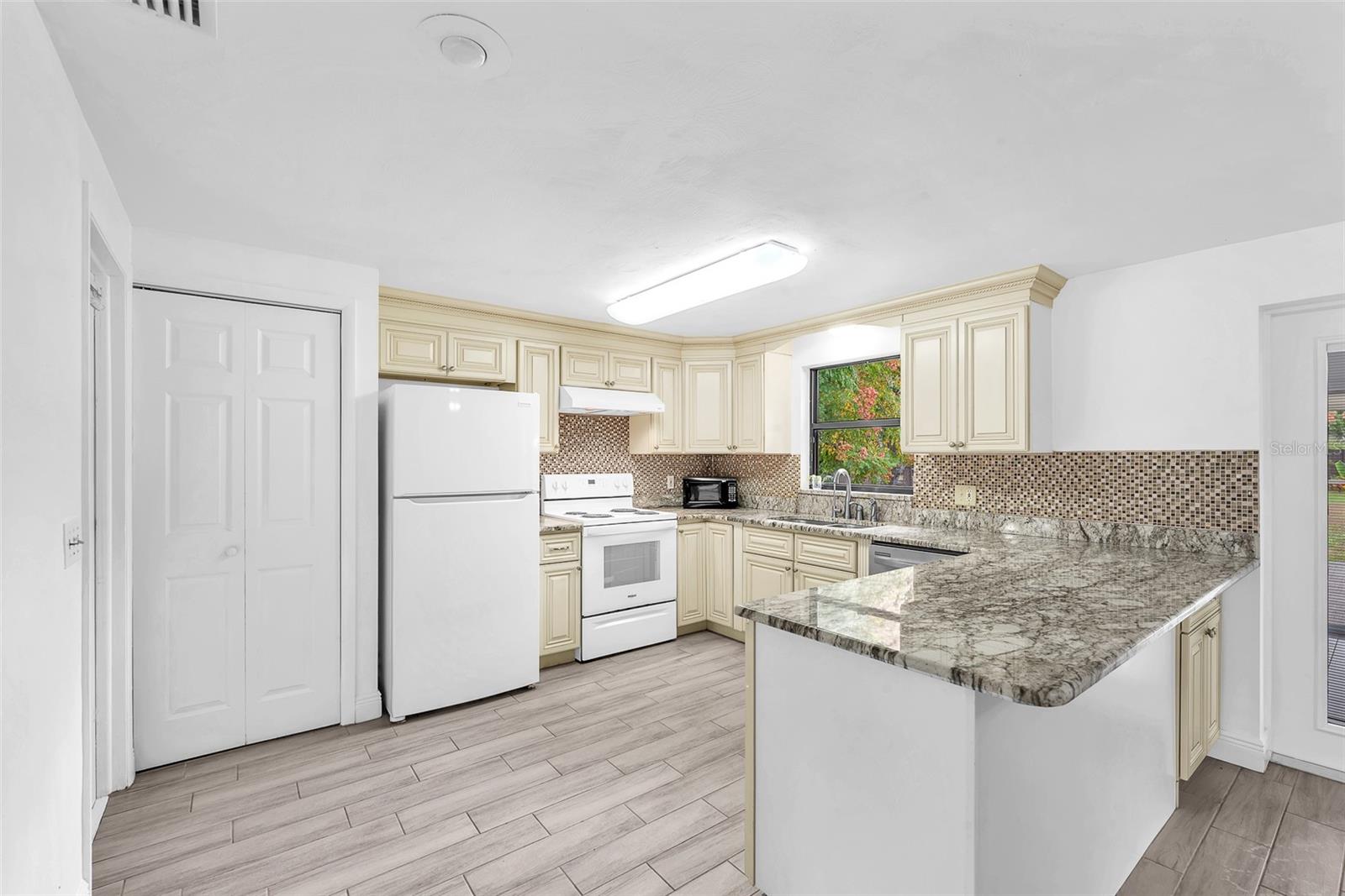 The remodeled kitchen features granite countertops, soft-close cabinetry, pull-out shelving in pantry, tile backsplash and upgraded Refrigerator and Range with hood in 2025