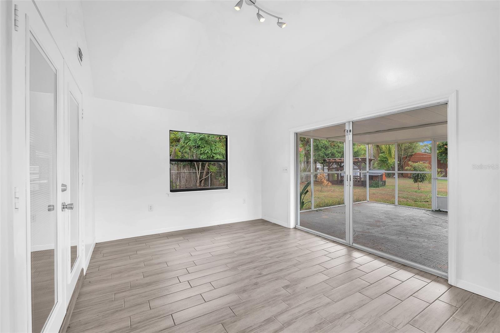 15' x 11' Florida bonus room with a vaulted ceiling and large sliding door leading to an enclosed screened in porch.