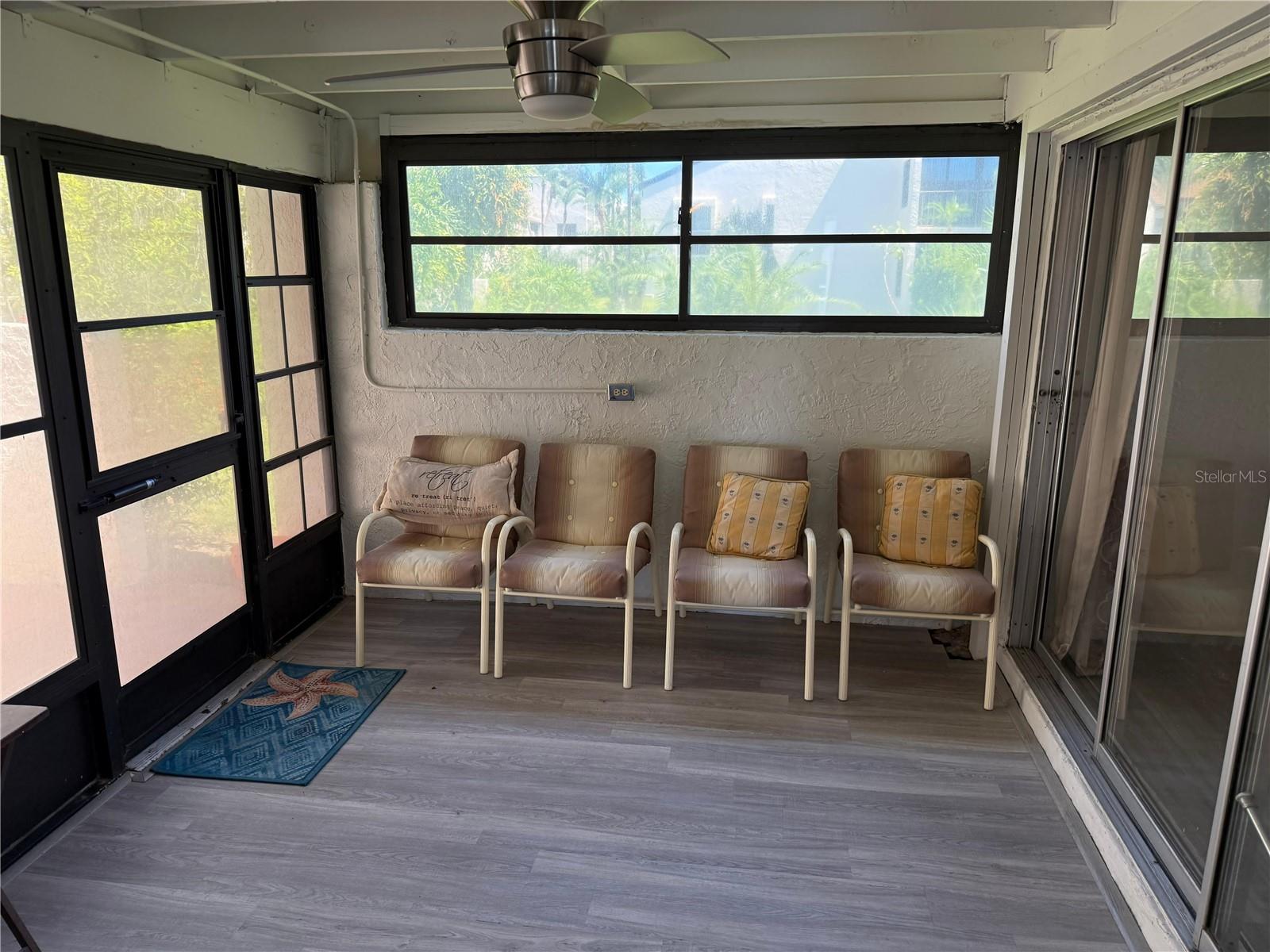 View from the dining area to the Florida room the primary bedroom on your right, the patio out the door to your left. Ceiling fan included. plenty of early morning light comes into your unit from here!