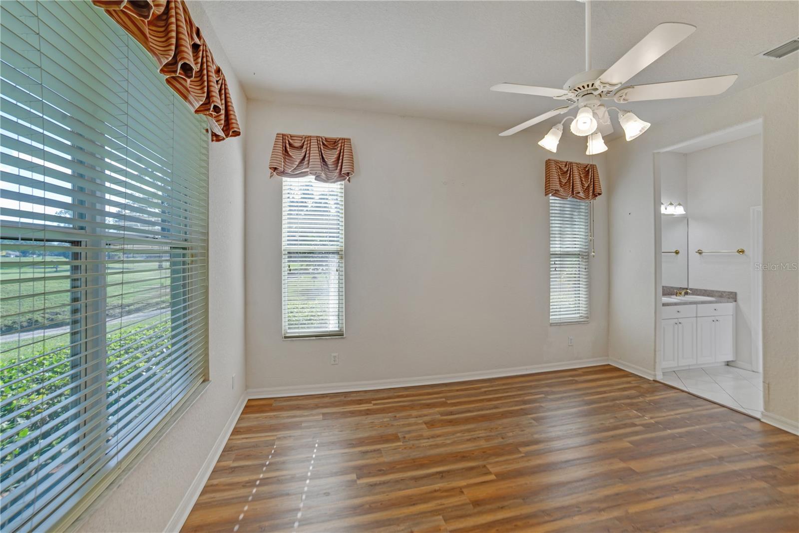 NATURAL LIGHT AND BEAUTIFUL VIEWS FROM THE PRIMARY BEDROOM FEATURING EN SUITE, CEILING FAN AND LAMINATE FLOORING