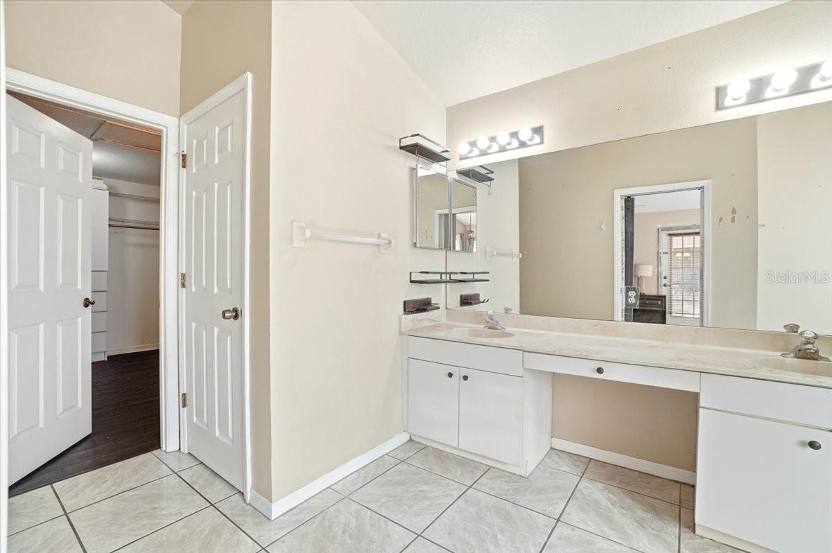 Primary bathroom with dual sinks and walk-in closet entry