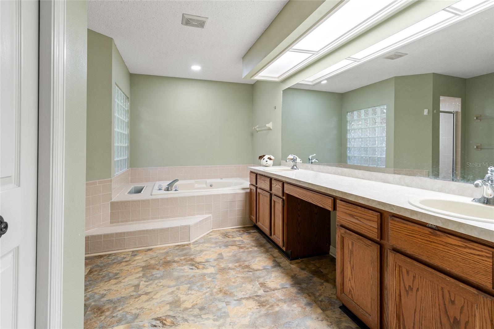 Primary Bathroom w/ large double vanities, garden tub, shower and private toilet