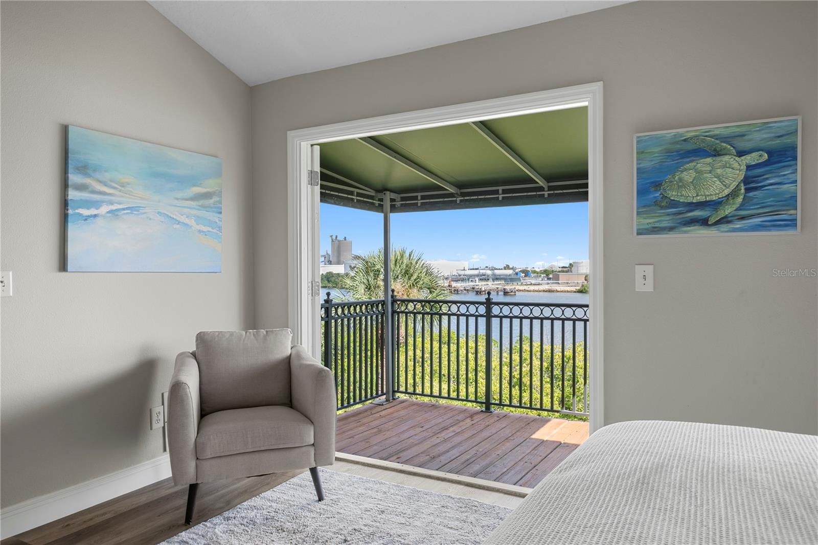 The primary bedroom features private balcony access, showcasing waterfront views