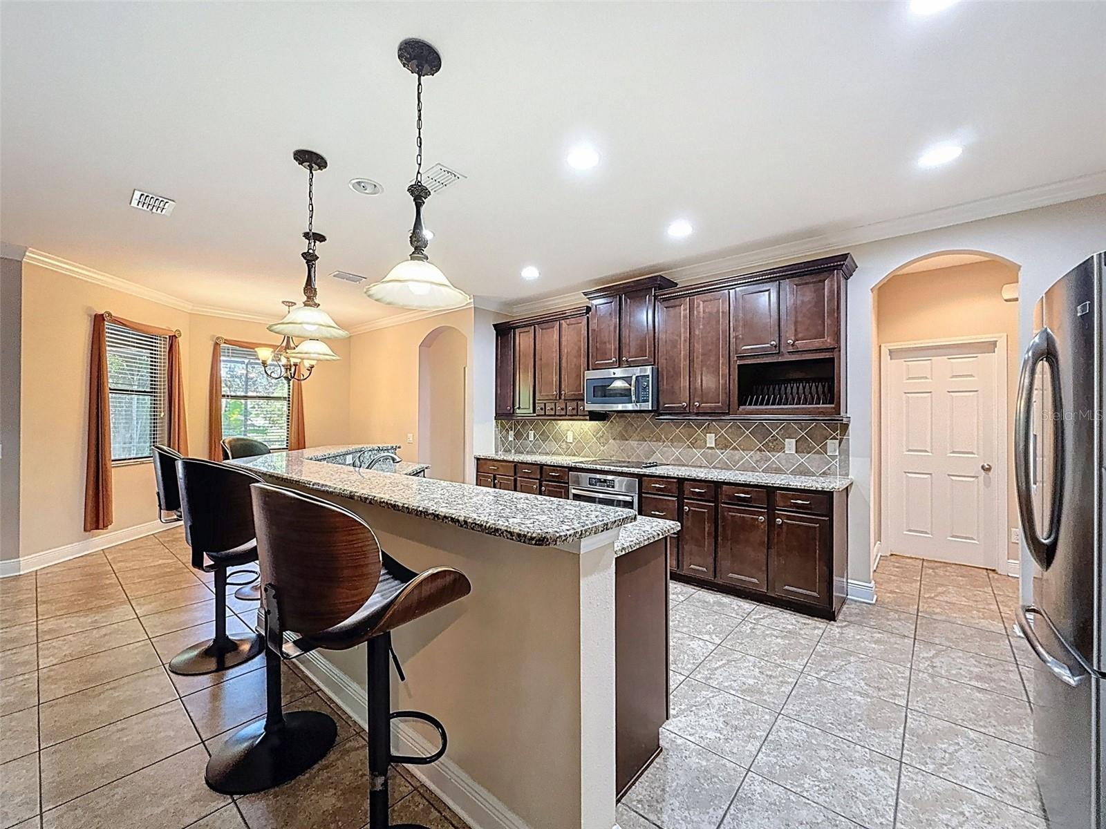 Expansive gourmet kitchen with beautiful tile backsplash, 42" cherry cabinets with crown molding, extensive cabinets for storage and a large walk in lighted pantry!