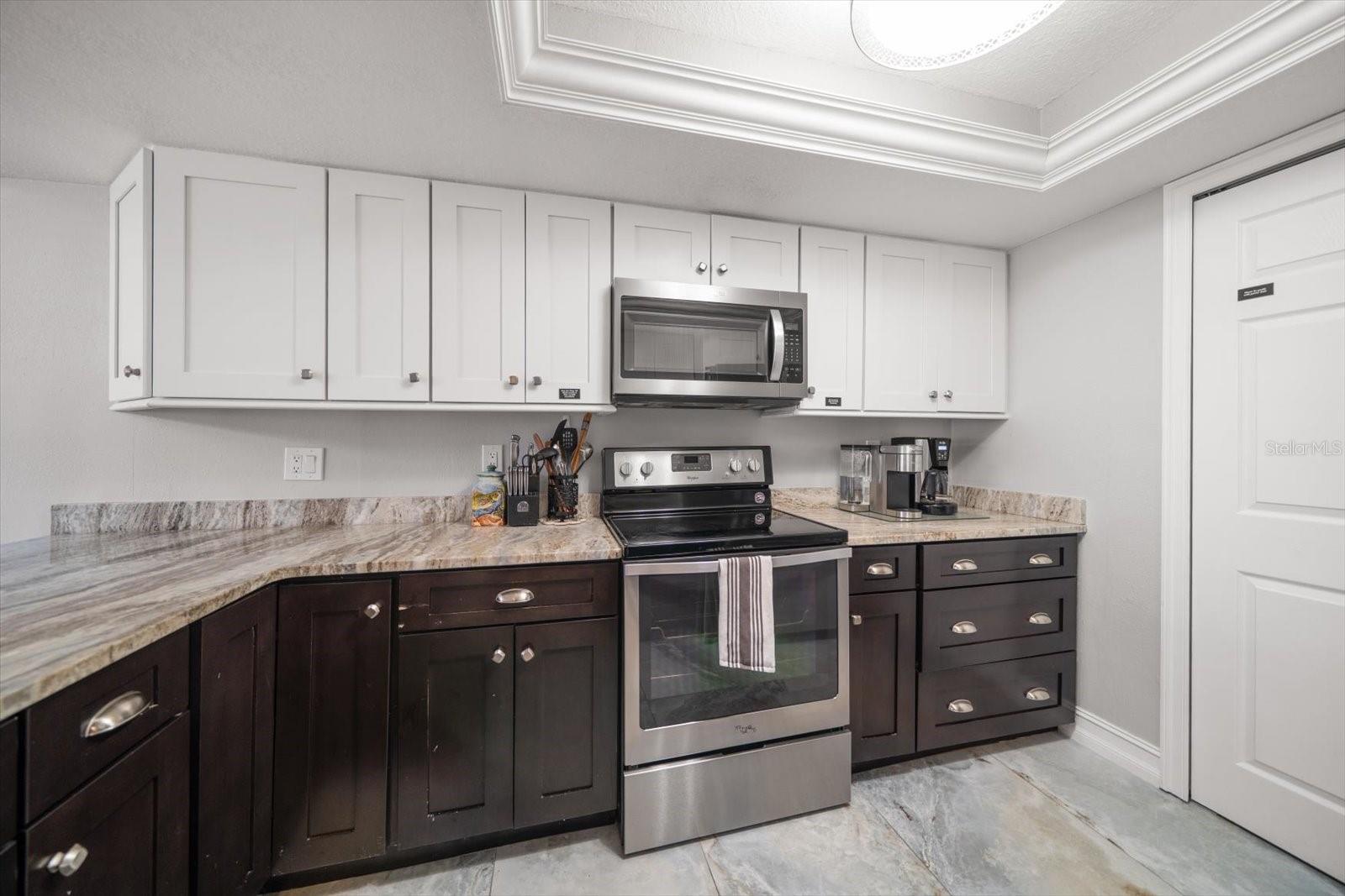 Attractive cabinetry enhanced by stone counters and porcelain flooring.